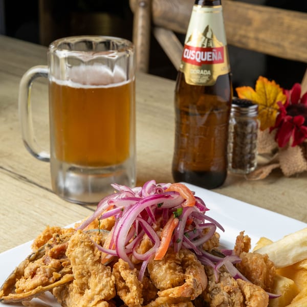 Fried seafood platter with red onion and pepper garnish, served with a beer mug and bottle.