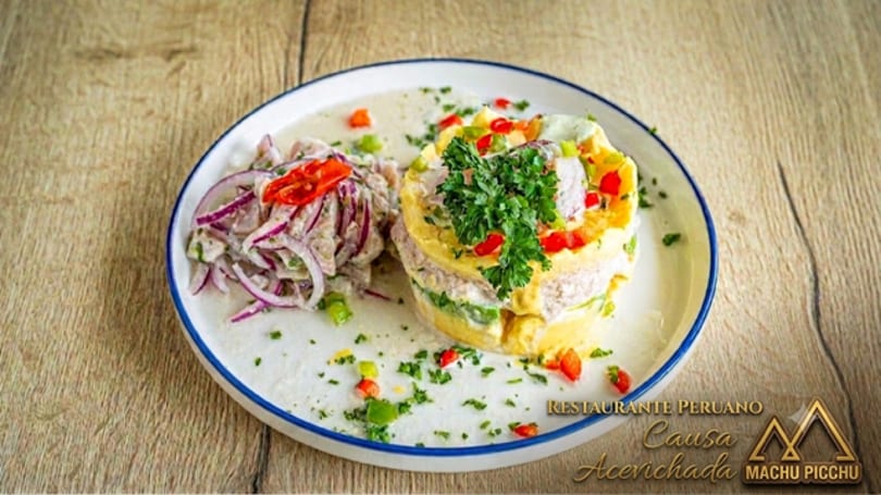 Peruvian causa acevichada, a layered potato dish with ceviche, on a white plate.