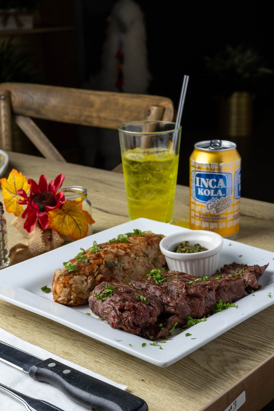 Grilled steak and rice with green onions, a side of green sauce, and Inca Kola.